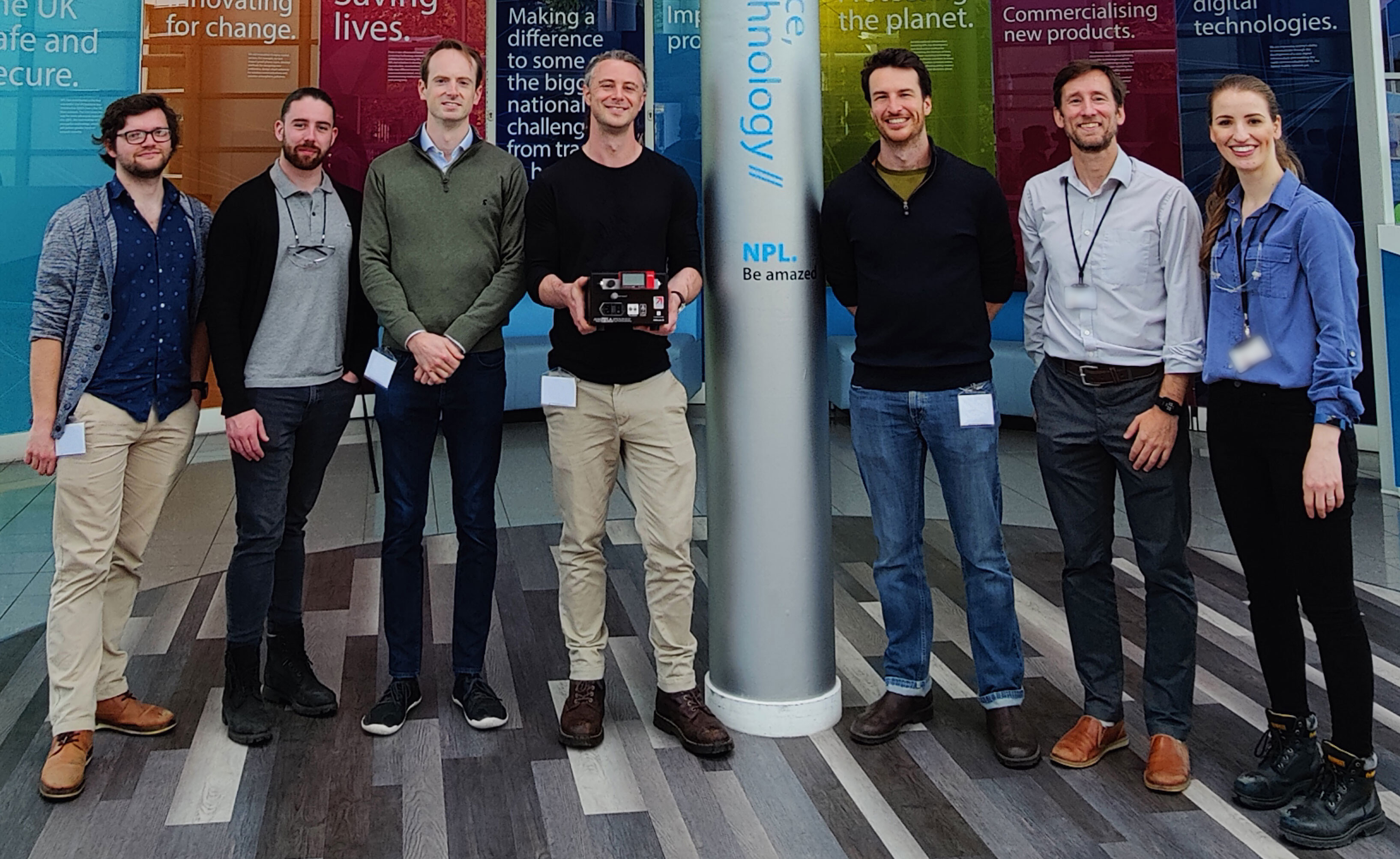 The Fourth State team during their visit to NPL alongside members of the Gas Metrology group. From left to right; Phillip Thomas, joint PhD student from the University of Surrey and Fourth State; Calum Bavin, Gas Metrology Scientist; Gavin Sandison, Fourth State VP of Engineering; Thomas Harle, Fourth State CEO and Founder; Tom Wantock, Fourth State Research and Innovation Manager; Dave Worton, Gas Metrology Principal Scientist; and Sivan Van Aswegen, Gas Metrology Higher Scientist. Other members of the project team not in the photo are: Nick Martin , Air Quality and Aerosol Metrology Principal Scientist and Rod Robinson, Emissions and Atmospheric Metrology Principal Scientist.