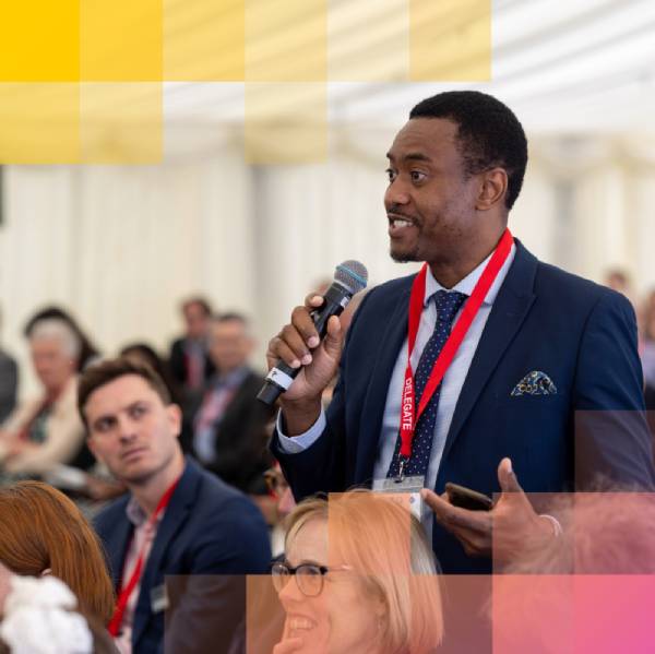 Attendee speaking into a microphone during a panel discussion at the NPL Industrial Innovation Summit, with delegates participating in a business innovation and networking event.